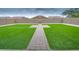 Landscaped backyard featuring green turf, a paved walkway, and a privacy wall at 25437 W Mahoney Ave, Buckeye, AZ 85326