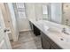 Bathroom showcasing a dual sink vanity with a large mirror and wood-look floors, complemented by ample natural light at 25437 W Mahoney Ave, Buckeye, AZ 85326