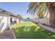 Beautiful backyard featuring lush artificial grass, a pool in the distance, and a covered patio at 3015 E Dahlia Dr, Phoenix, AZ 85032