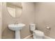 A well-maintained half bathroom features a pedestal sink, toilet, and neutral decor at 40049 W Hopper Dr, Maricopa, AZ 85138