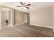 Large, carpeted bedroom showing access to a closet and bathroom with dark wood cabinets at 40049 W Hopper Dr, Maricopa, AZ 85138