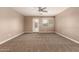 Spacious living room featuring plush carpeting, natural light, and a ceiling fan at 40049 W Hopper Dr, Maricopa, AZ 85138