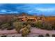 Exterior view of the home nestled in a desert landscape with mountain views at dusk at 40478 N 108Th Pl, Scottsdale, AZ 85262