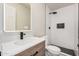 A modern bathroom with a white vanity, a decorative mirror, and a tiled shower stall with a black shower head at 6265 W Mariposa St, Phoenix, AZ 85033