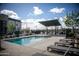 Community pool with clear blue water, lounge chairs, an awning, and green trees at 7531 E Billings St # 132, Mesa, AZ 85207