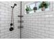 Close-up of a shower with white subway tile, bronze fixtures, and a shelf holding potted plants at 804 E Palmaire Ave, Phoenix, AZ 85020