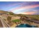 Sunset view of a backyard oasis with a swimming pool, putting green, desert landscaping, and scenic mountain backdrop at 8219 E Tesoro Cir, Mesa, AZ 85207