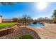Resort-style backyard with a lagoon pool, waterfall feature, putting green, and desert landscaping at 8219 E Tesoro Cir, Mesa, AZ 85207
