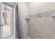 Walk-in shower featuring beige tile walls, neutral accent stripes, and a convenient corner shelf at 8219 E Tesoro Cir, Mesa, AZ 85207