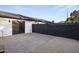 A private backyard area with a concrete patio, gravel accents, and a secure black block fence at 8409 E Clarendon Ave, Scottsdale, AZ 85251