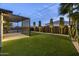 Backyard features a covered patio, artificial grass, and tastefully landscaped yard with trees and desert plants at 8409 E Clarendon Ave, Scottsdale, AZ 85251