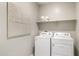 Well-lit laundry room with washer, dryer, shelf with towels, and modern design at 10616 W Sonrisas St, Tolleson, AZ 85353