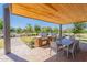 Outdoor kitchen area with built-in BBQ, dining table, and seating under a covered patio overlooking green space at 11107 E Ulysses Ave, Mesa, AZ 85212