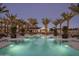 Inviting pool at dusk surrounded by palm trees, outdoor lounge seating, and manicured landscaping at 11300 N Casa Dega Dr # 1000, Surprise, AZ 85388