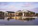 Elegant clubhouse with outdoor seating areas reflected in the calm waters of the pool and twilight sky at 11300 N Casa Dega Dr # 1058, Surprise, AZ 85388