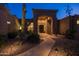 Inviting home entrance with arched doorway, desert landscaping, and illuminated pathway at 12083 E Wethersfield Dr, Scottsdale, AZ 85259