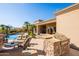 Well-equipped outdoor kitchen and lounge area with a built-in grill and comfortable seating by the pool at 12083 E Wethersfield Dr, Scottsdale, AZ 85259