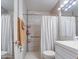 Neutral-toned bathroom features a tiled shower with built-in shelves and grab bar, a white shower curtain, and bright vanity lighting at 1340 E Townley Ave, Phoenix, AZ 85020