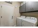 Laundry room featuring a washer and dryer, gray storage cabinets, a door, and a 'Laundry Co' sign above at 1440 W Christie Lyn Ln, San Tan Valley, AZ 85144