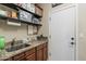 A practical laundry area showcasing a sink, granite countertop, dark wood cabinets, and shelving units for storage at 1440 W Christie Lyn Ln, San Tan Valley, AZ 85144