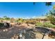 Serene backyard featuring mature landscaping, comfortable seating, and decorative stone elements, ideal for relaxation at 15840 W Falcon Ridge Dr, Sun City West, AZ 85375