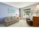 Inviting living room with comfortable plaid couch, cozy armchair, and a bright window with a view of the outdoor greenery at 15840 W Falcon Ridge Dr, Sun City West, AZ 85375