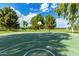 Full basketball court featuring a vibrant green surface and surrounded by mature trees in a well-maintained park at 16939 W Marconi Ave, Surprise, AZ 85388