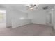 Spacious living room with neutral walls and carpet featuring a ceiling fan and multiple entryways at 16939 W Marconi Ave, Surprise, AZ 85388