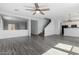 Open-concept living space with wood laminate floors, fan and view into the kitchen and staircase at 16939 W Marconi Ave, Surprise, AZ 85388