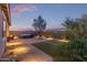 Cozy backyard featuring a hot tub, lounge chairs, artificial turf, and desert landscaping at twilight at 17796 W Sandy Rd, Goodyear, AZ 85338