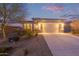 Inviting single-story home at dusk featuring a two-car garage and desert landscaping at 17796 W Sandy Rd, Goodyear, AZ 85338