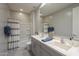 Bathroom with a double vanity with gray cabinetry, a large mirror, and a shower/tub combo with blue towels at 18385 W Devonshire Ave, Goodyear, AZ 85395