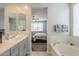 Bathroom featuring a double vanity, soaking tub, and views of the bedroom at 18385 W Devonshire Ave, Goodyear, AZ 85395