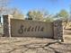 The Sedella community monument sign stands in a desert landscape with trees in the background, marking the entrance at 18385 W Devonshire Ave, Goodyear, AZ 85395