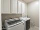 A laundry room with overhead cabinets and newer washer and dryer appliances at 18385 W Devonshire Ave, Goodyear, AZ 85395