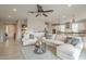 Bright open-concept living room with neutral decor, ceiling fan, and seamless flow to the kitchen at 18385 W Devonshire Ave, Goodyear, AZ 85395