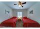 Bright bedroom featuring two twin beds with red bedding and a ceiling fan with lighting at 2101 S Meridian Rd # 190, Apache Junction, AZ 85120