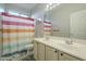 Bright bathroom with double sinks, colorful shower curtain, and tile flooring at 25622 N Singbush Loop, Phoenix, AZ 85083