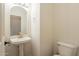 Well-lit powder room featuring a pedestal sink with a gold faucet, a mirror, and a toilet for added convenience at 25622 N Singbush Loop, Phoenix, AZ 85083