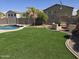 Backyard with firepit, seating area, mature landscaping, and grassy turf at 28273 N Castle Rock Dr, San Tan Valley, AZ 85143