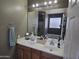 Well-lit bathroom featuring a double sink vanity with storage, a large mirror, and a peek into the separate bathtub at 28273 N Castle Rock Dr, San Tan Valley, AZ 85143