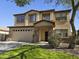 Two-story home featuring a two-car garage, manicured lawn, and a mix of stone and stucco finishes at 28273 N Castle Rock Dr, San Tan Valley, AZ 85143