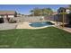 Sparkling pool with waterfall feature surrounded by artificial turf at 28273 N Castle Rock Dr, San Tan Valley, AZ 85143