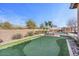 Backyard featuring a putting green, outdoor kitchen, a sparkling pool and lush landscaping at 2928 E Palm St, Mesa, AZ 85213