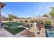 An outdoor kitchen featuring a stainless steel grill, with a putting green and refreshing pool in the background at 2928 E Palm St, Mesa, AZ 85213