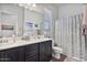 Well-lit bathroom with a double vanity, framed mirror, and a shower with a patterned curtain at 2928 E Palm St, Mesa, AZ 85213