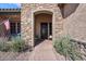 Close-up of the front entrance with a decorative stone archway, an elegant door, and desert landscaping at 2928 E Palm St, Mesa, AZ 85213