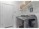 Clean, bright laundry room featuring side-by-side washer and dryer, storage shelves, and a utility door at 3408 S 184Th Ln, Goodyear, AZ 85338