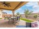 Covered patio with pavers features an outdoor dining set, wicker furniture, and views of the landscaped yard at 3408 S 184Th Ln, Goodyear, AZ 85338