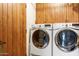 Laundry room features side by side white washer and dryer and wooden cabinets and door at 36601 N Mule Train N Rd # D16, Carefree, AZ 85377